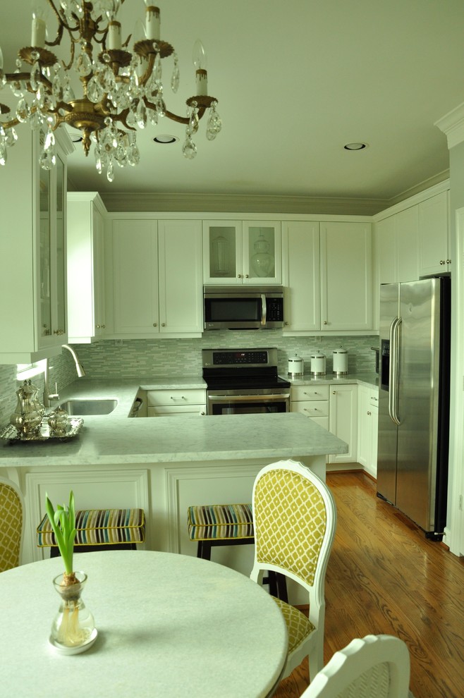 Klassisk inredning av ett litet linjärt kök och matrum, med en undermonterad diskho, luckor med glaspanel, vita skåp, marmorbänkskiva, vitt stänkskydd, stänkskydd i glaskakel, rostfria vitvaror, mellanmörkt trägolv och en köksö