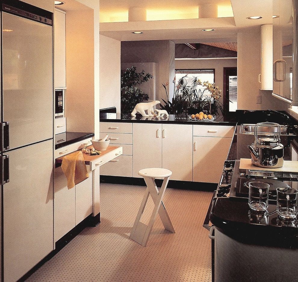 Foto på ett avskilt, litet funkis l-kök, med en nedsänkt diskho, släta luckor, vita skåp, bänkskiva i koppar, svart stänkskydd, stänkskydd i sten, vita vitvaror och linoleumgolv