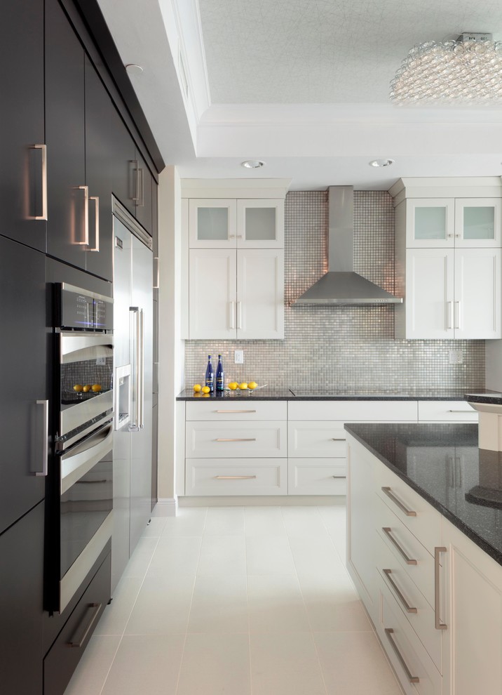Mid-sized trendy ceramic tile and white floor kitchen photo in Miami with recessed-panel cabinets, white cabinets, quartz countertops, metallic backsplash, mosaic tile backsplash, stainless steel appliances and an island