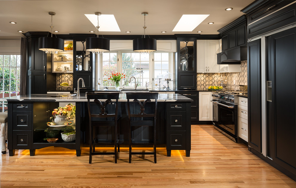 Klassische Küche in L-Form mit schwarzen Elektrogeräten, profilierten Schrankfronten, schwarzen Schränken, braunem Holzboden und Kücheninsel in Vancouver