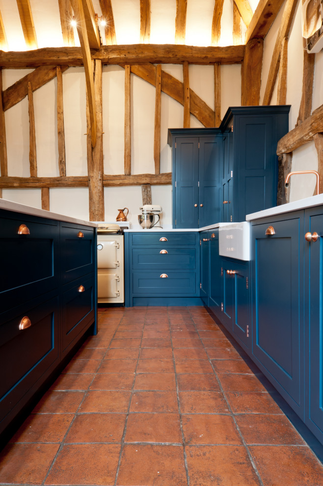 This is an example of a medium sized bohemian open plan kitchen in Kent with a double-bowl sink, shaker cabinets, blue cabinets, quartz worktops, terracotta flooring, an island, brown floors and white worktops.