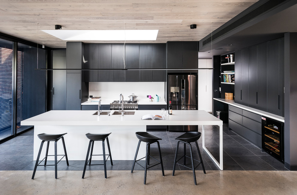 Photo of a large modern kitchen in Melbourne with flat-panel cabinets, engineered stone countertops, white splashback, glass sheet splashback, stainless steel appliances, porcelain flooring, an island, white worktops, a double-bowl sink and black floors.