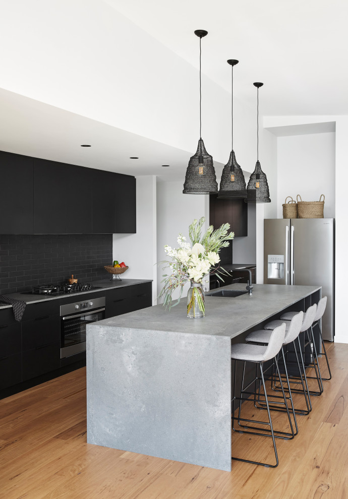 Open concept kitchen - mid-sized modern galley light wood floor open concept kitchen idea in Sydney with a double-bowl sink, flat-panel cabinets, black cabinets, quartz countertops, black backsplash, ceramic backsplash, black appliances, an island and gray countertops