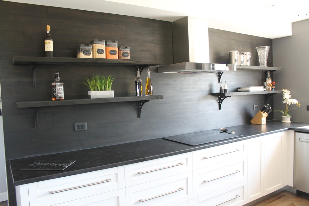 Inredning av ett modernt svart svart kök, med skåp i shakerstil, vita skåp, svart stänkskydd och stänkskydd i trä