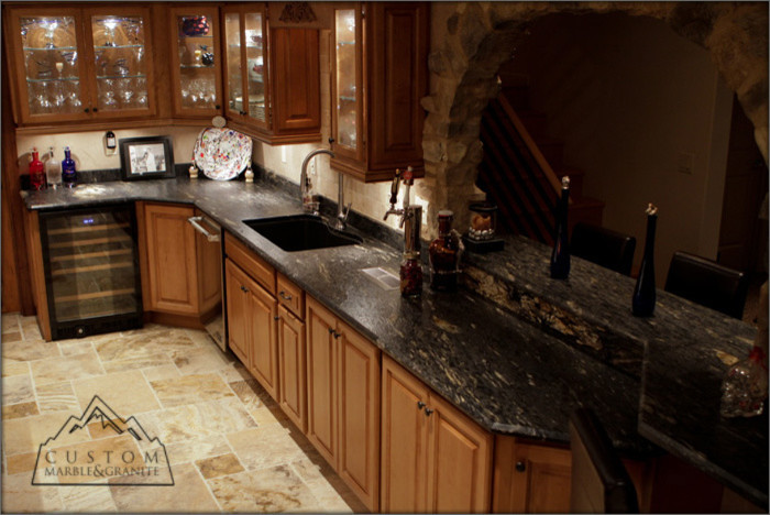 Inredning av ett medelhavsstil kök, med granitbänkskiva, beige stänkskydd, stänkskydd i stenkakel, rostfria vitvaror och travertin golv