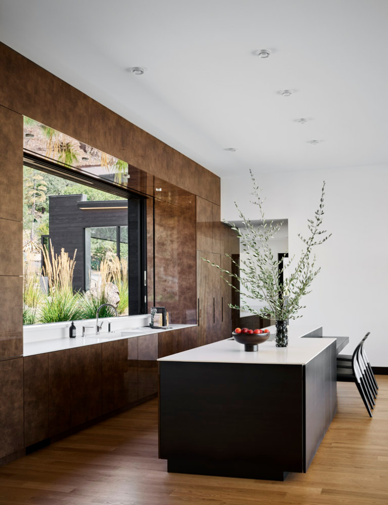 Immagine di una cucina minimalista con ante lisce, ante marroni, pavimento in legno massello medio, pavimento marrone e top bianco
