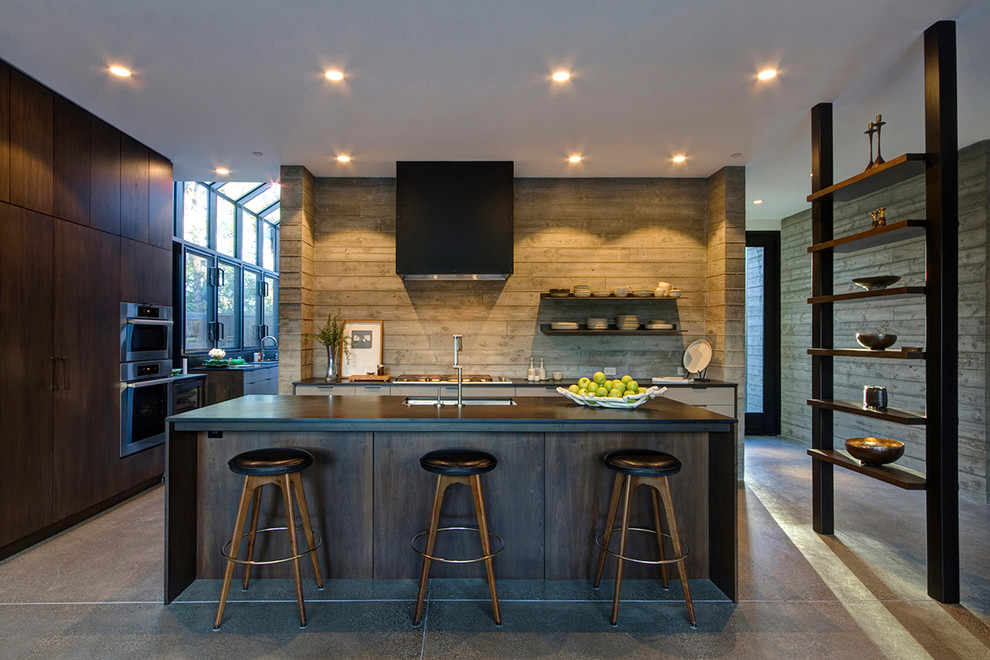 Photo of a large rural l-shaped open plan kitchen in San Francisco with a submerged sink, flat-panel cabinets, dark wood cabinets, integrated appliances, concrete flooring and an island.