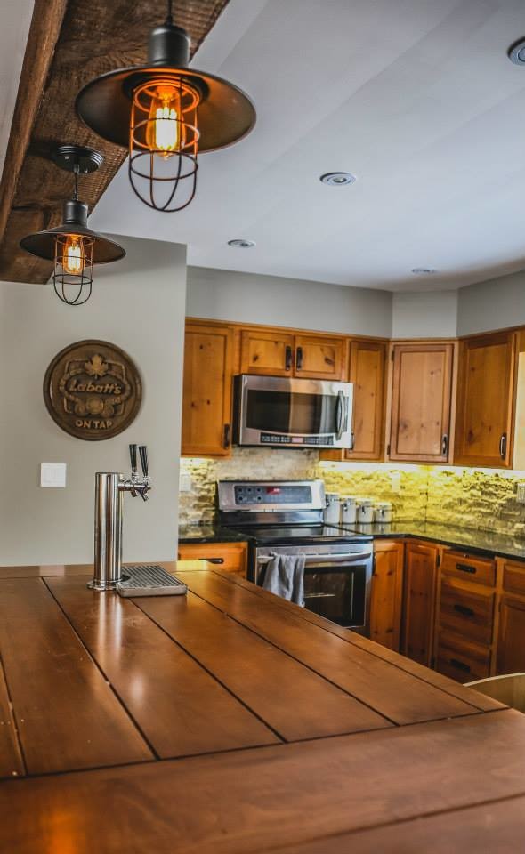 Foto di una cucina stile rurale con lavello sottopiano, top in legno, paraspruzzi beige, paraspruzzi con piastrelle in pietra, elettrodomestici in acciaio inossidabile e pavimento in gres porcellanato