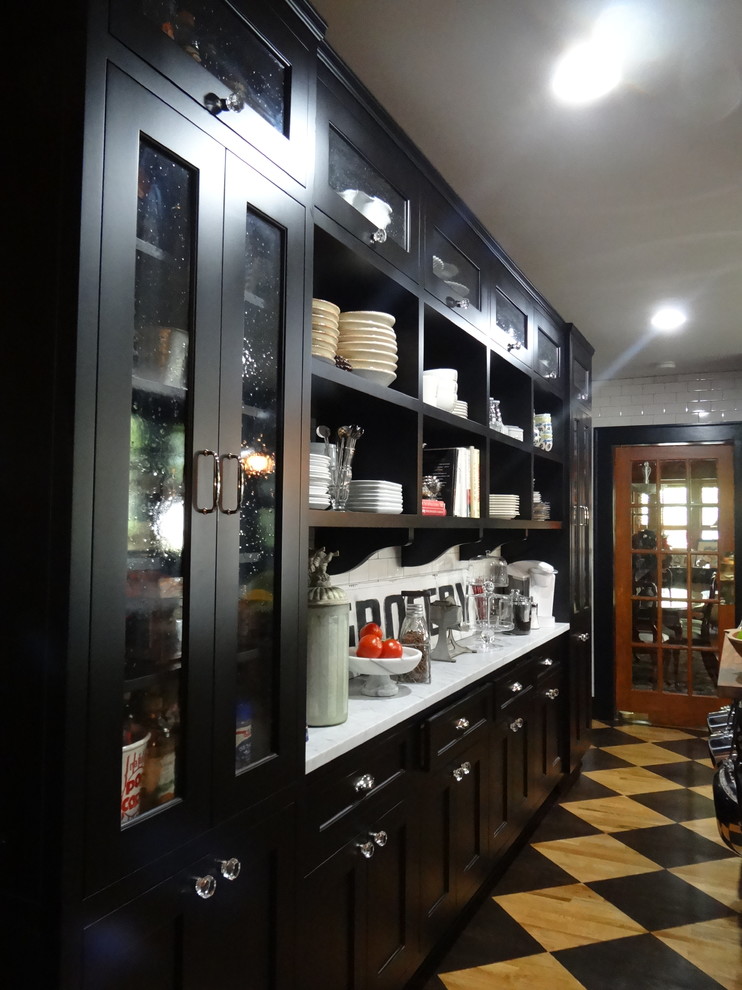 Inredning av ett klassiskt avskilt, mellanstort kök, med en rustik diskho, svarta skåp, marmorbänkskiva, vitt stänkskydd, stänkskydd i tunnelbanekakel, rostfria vitvaror, målat trägolv, en köksö, skåp i shakerstil och svart golv