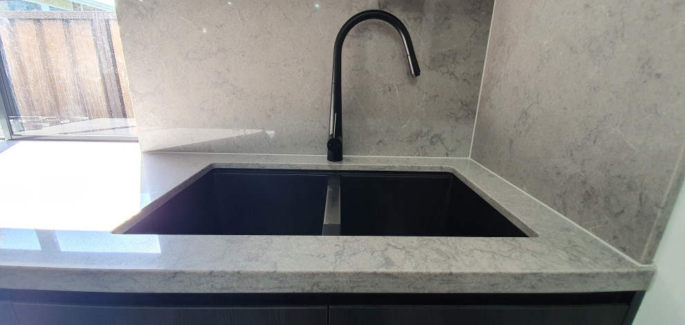Inspiration for an expansive modern galley open plan kitchen in Sydney with a submerged sink, flat-panel cabinets, black cabinets, engineered stone countertops, grey splashback, engineered quartz splashback, black appliances, multiple islands and grey worktops.