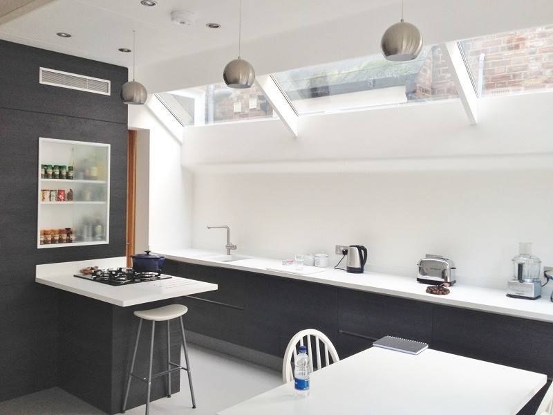 This is an example of a medium sized contemporary kitchen in London with black cabinets and a breakfast bar.