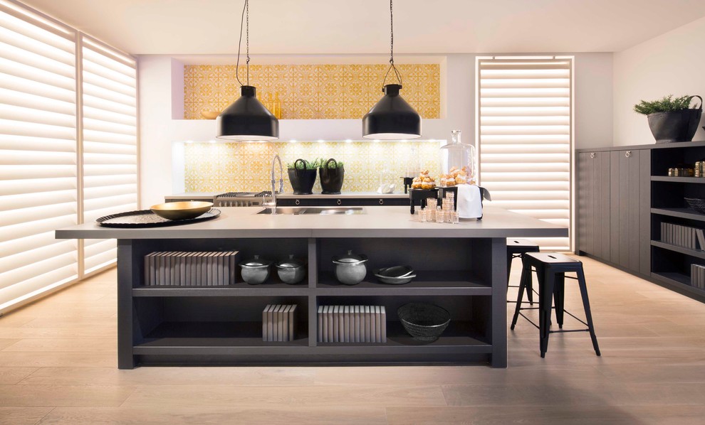 Immagine di un cucina con isola centrale design chiuso con ante nere, paraspruzzi giallo e elettrodomestici in acciaio inossidabile