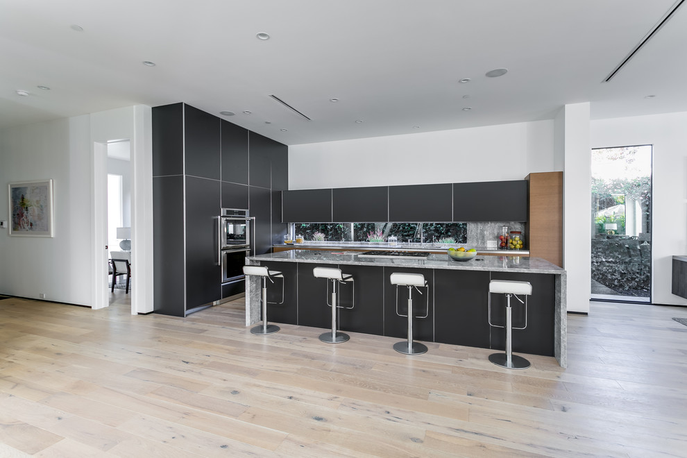 Inredning av ett modernt kök, med en dubbel diskho, släta luckor, svarta skåp, marmorbänkskiva, flerfärgad stänkskydd, rostfria vitvaror, mellanmörkt trägolv och en köksö