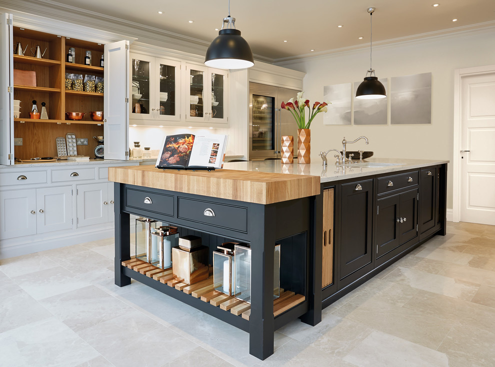 This is an example of a large contemporary single-wall enclosed kitchen in Manchester with a belfast sink, beaded cabinets, black cabinets, composite countertops, white splashback, stone slab splashback, stainless steel appliances, marble flooring and an island.