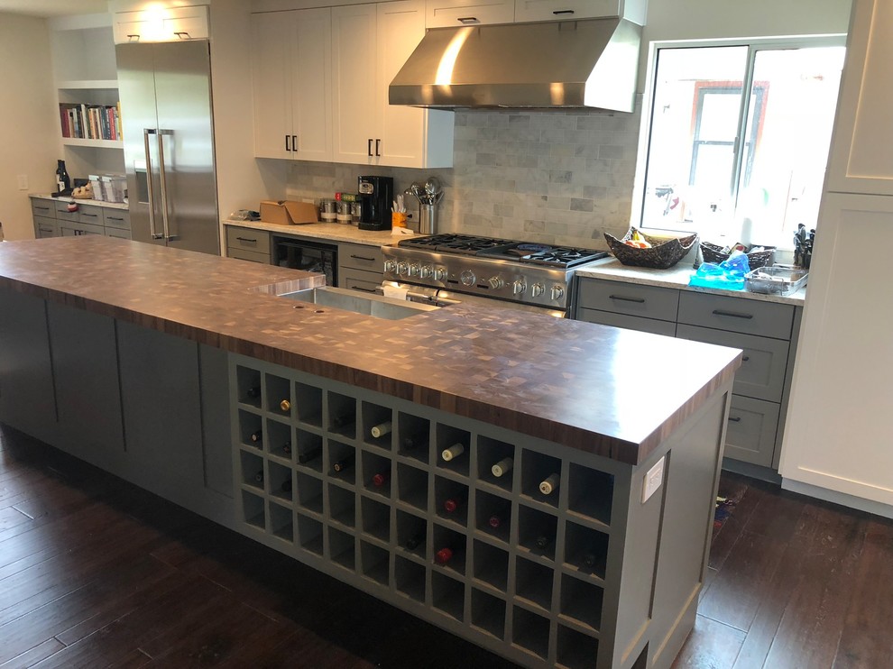 Inspiration for an expansive contemporary galley open plan kitchen in Austin with a submerged sink, raised-panel cabinets, grey cabinets, granite worktops, black appliances, dark hardwood flooring, an island and brown floors.
