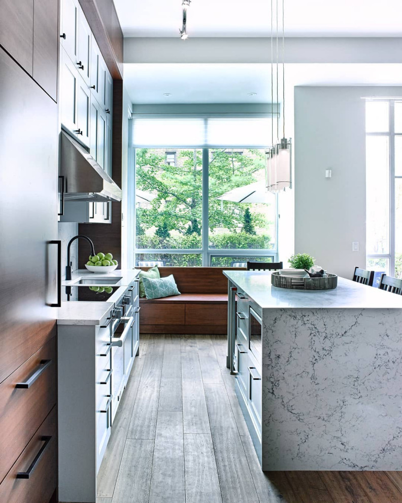 Inspiration for a mid-sized contemporary galley medium tone wood floor and brown floor kitchen remodel in Toronto with marble countertops, an island, an undermount sink, flat-panel cabinets, medium tone wood cabinets, paneled appliances and gray countertops