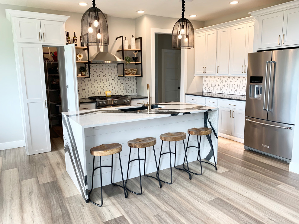 Inspiration for a medium sized traditional l-shaped kitchen/diner in Other with a belfast sink, recessed-panel cabinets, white cabinets, engineered stone countertops, white splashback, ceramic splashback, stainless steel appliances, medium hardwood flooring, an island, brown floors and multicoloured worktops.