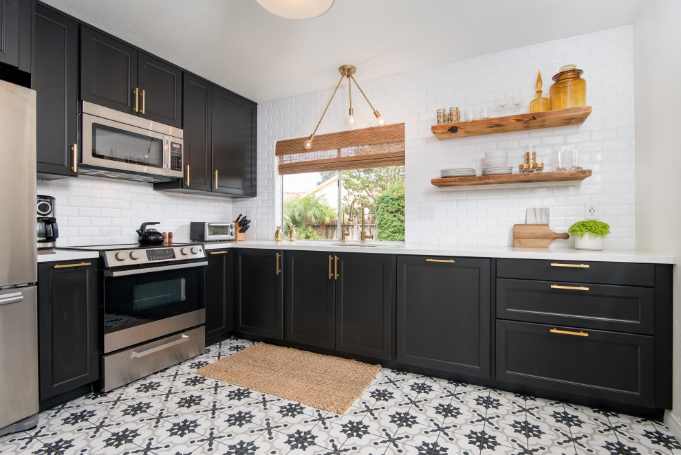 Design ideas for a classic l-shaped kitchen in San Diego with recessed-panel cabinets, black cabinets, white splashback, metro tiled splashback, stainless steel appliances, multi-coloured floors and white worktops.