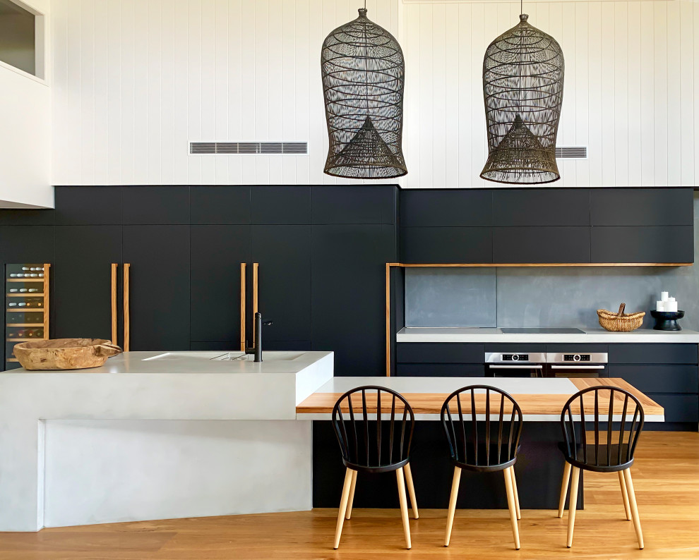 Esempio di una cucina design con ante lisce, ante nere, top in cemento, paraspruzzi grigio, top grigio, lavello integrato, elettrodomestici da incasso, pavimento in legno massello medio e pavimento marrone