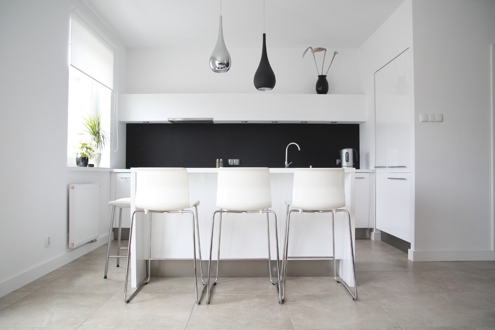 Cette image montre une cuisine parallèle design avec un placard à porte plane, des portes de placard blanches et une crédence noire.