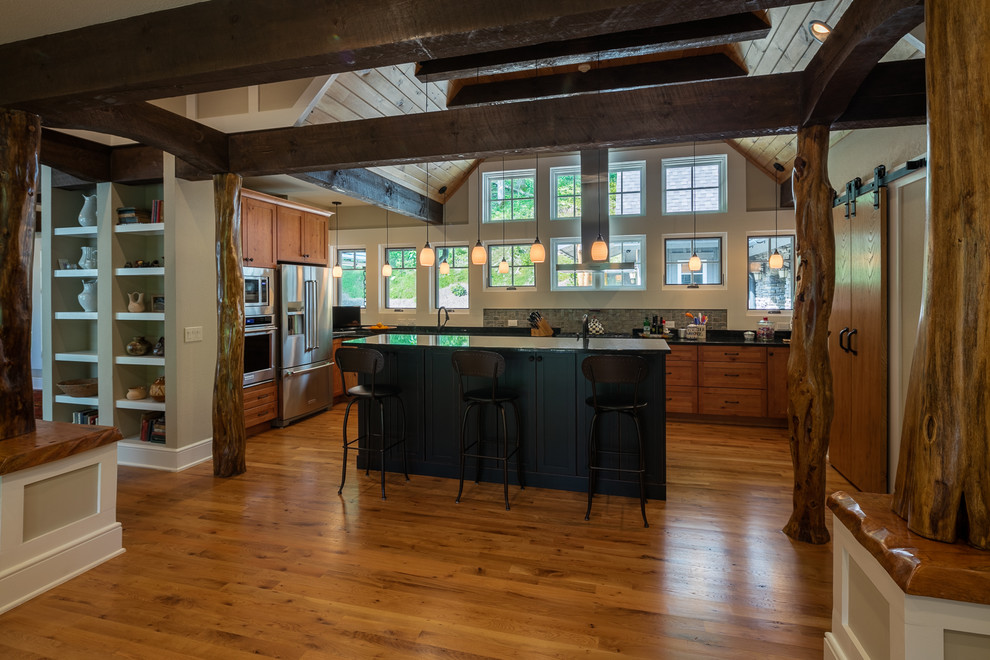 Exempel på ett avskilt, mellanstort rustikt u-kök, med en dubbel diskho, släta luckor, skåp i mellenmörkt trä, granitbänkskiva, grått stänkskydd, stänkskydd i sten, rostfria vitvaror, mellanmörkt trägolv, en köksö och brunt golv