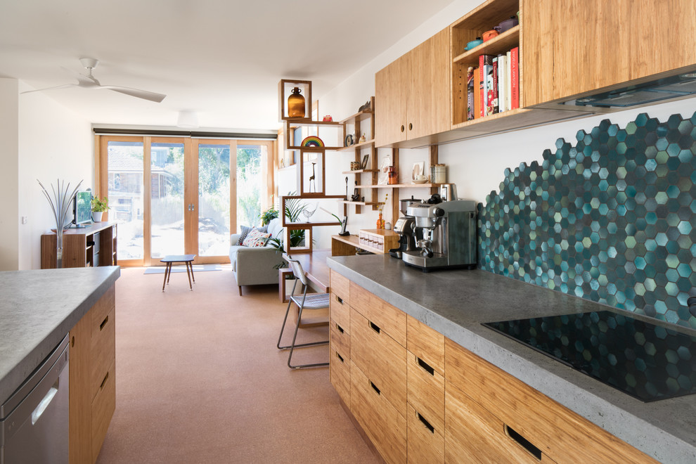 Foto på ett mellanstort funkis kök, med en undermonterad diskho, släta luckor, skåp i ljust trä, bänkskiva i betong, grönt stänkskydd, stänkskydd i stenkakel, korkgolv, en köksö och beiget golv