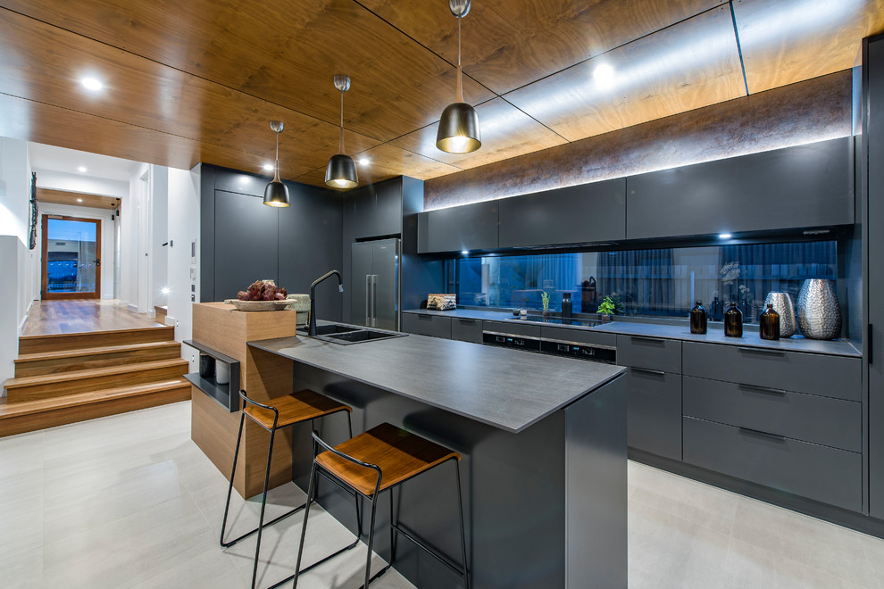 Inspiration for a contemporary galley kitchen in Canberra - Queanbeyan with a built-in sink, flat-panel cabinets, grey cabinets, window splashback, black appliances, an island, grey floors and grey worktops.