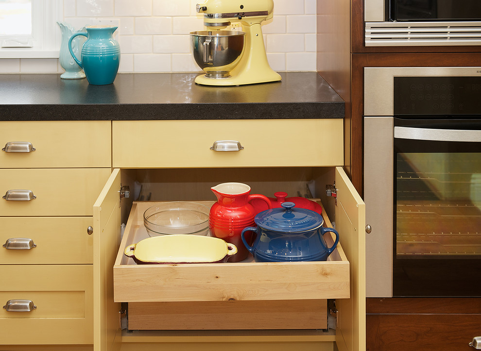 Exempel på ett mellanstort lantligt kök, med en rustik diskho, skåp i shakerstil, gula skåp, bänkskiva i kvarts, vitt stänkskydd, stänkskydd i tunnelbanekakel, rostfria vitvaror, mellanmörkt trägolv, en köksö och brunt golv