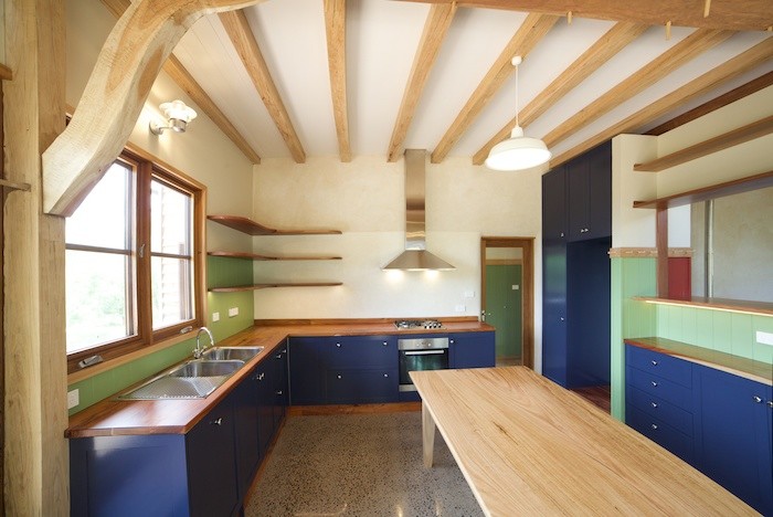 Exempel på ett avskilt, mellanstort amerikanskt u-kök, med en dubbel diskho, skåp i shakerstil, blå skåp, träbänkskiva, grönt stänkskydd, rostfria vitvaror, betonggolv och en köksö