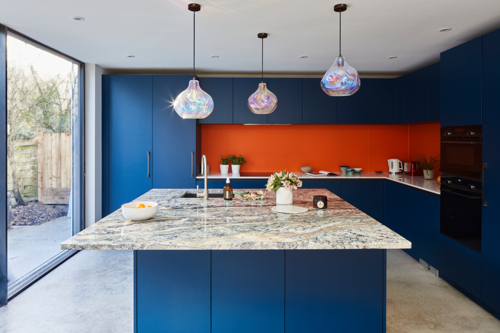 Ispirazione per una grande cucina minimal con ante lisce, ante blu, top in quarzite, paraspruzzi arancione, paraspruzzi con lastra di vetro, elettrodomestici in acciaio inossidabile, pavimento in cemento e pavimento grigio