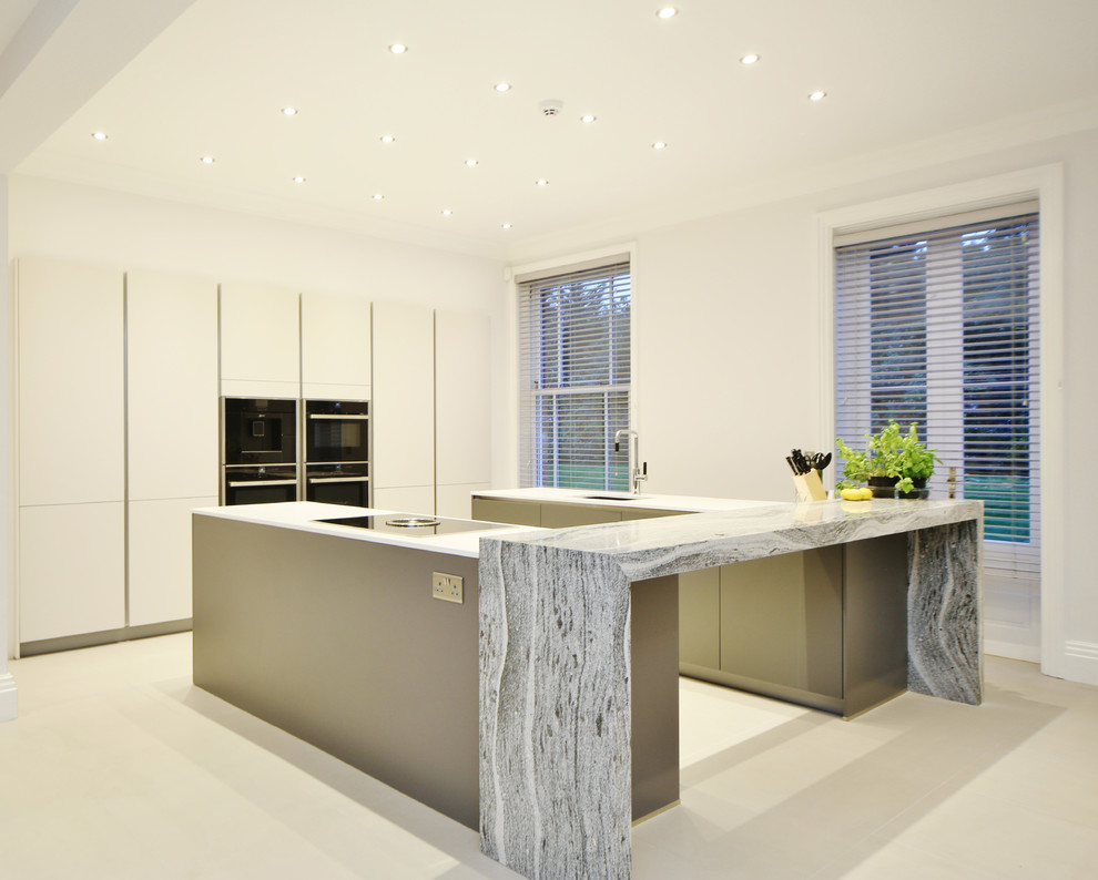 Large contemporary u-shaped kitchen/diner in Surrey with a submerged sink, flat-panel cabinets, grey cabinets, quartz worktops, black appliances, porcelain flooring, multiple islands, white floors and white worktops.