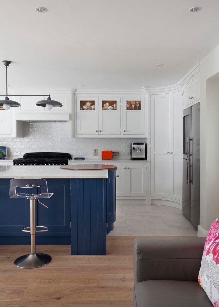 Design ideas for a large traditional l-shaped open plan kitchen in Dublin with an integrated sink, shaker cabinets, blue cabinets, quartz worktops, ceramic splashback, black appliances, light hardwood flooring, an island and brown floors.