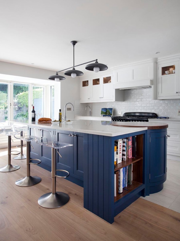 Inspiration för stora moderna kök, med en integrerad diskho, skåp i shakerstil, blå skåp, bänkskiva i kvartsit, stänkskydd i keramik, svarta vitvaror, ljust trägolv, en köksö och brunt golv