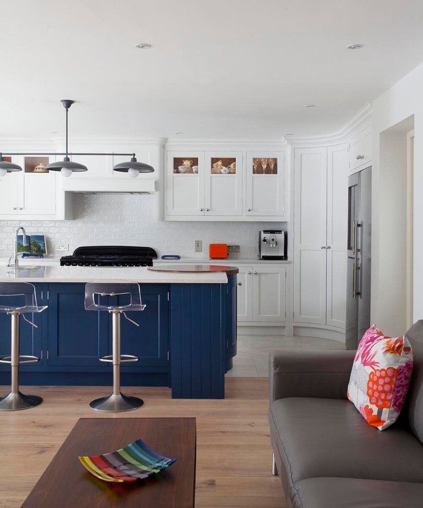 Exempel på ett stort klassiskt kök, med en integrerad diskho, skåp i shakerstil, blå skåp, bänkskiva i kvartsit, stänkskydd i keramik, svarta vitvaror, ljust trägolv, en köksö och brunt golv