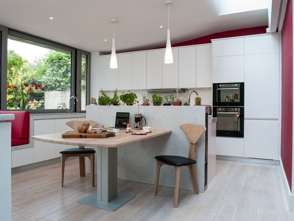 Photo of a contemporary kitchen in Dublin with flat-panel cabinets, white cabinets and an island.
