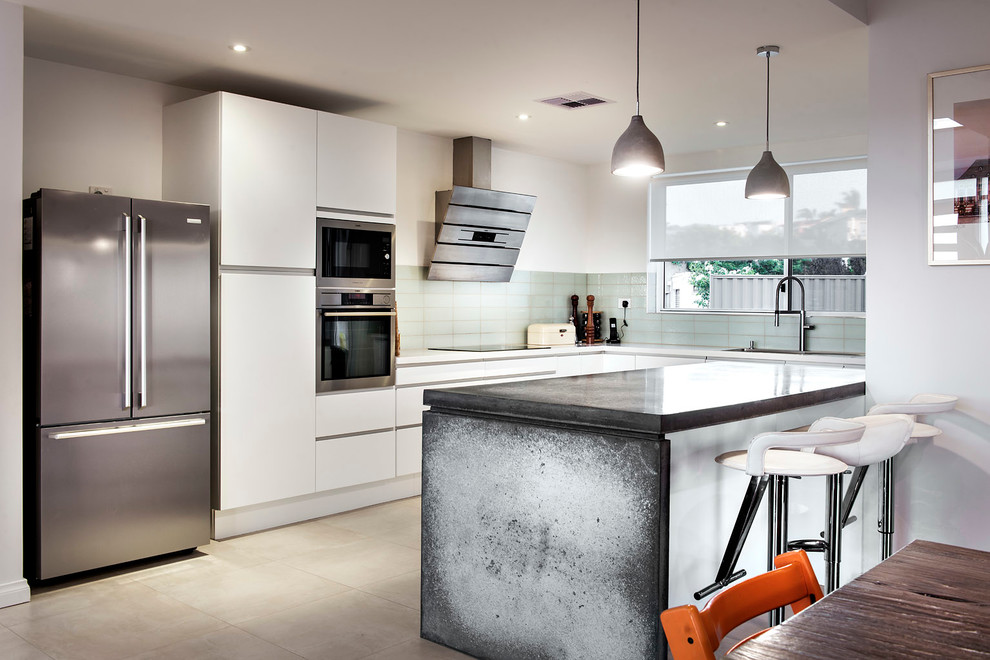 Modelo de cocina contemporánea con fregadero encastrado, armarios con paneles lisos, puertas de armario blancas, salpicadero gris y electrodomésticos de acero inoxidable