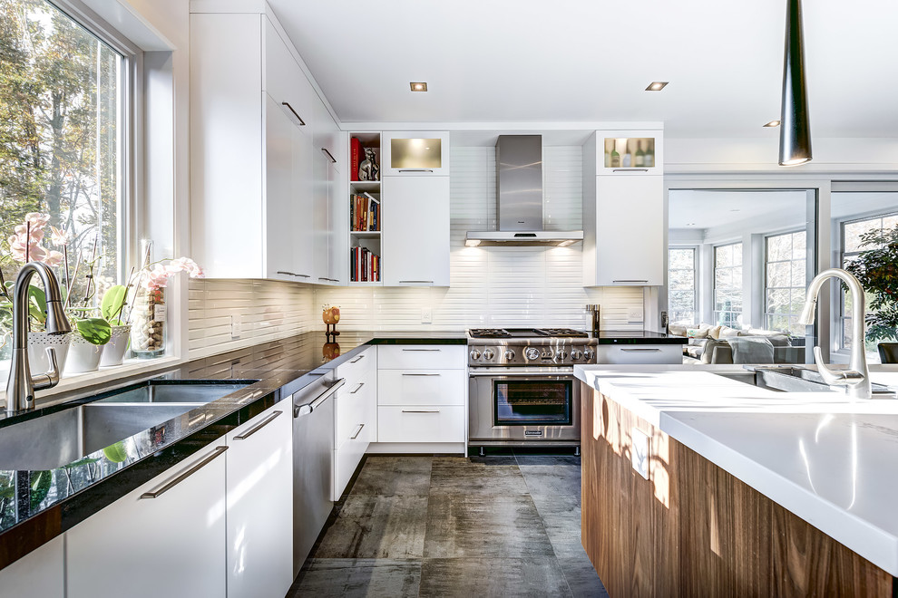 This is an example of a medium sized contemporary u-shaped kitchen/diner in Montreal with a submerged sink, flat-panel cabinets, white cabinets, engineered stone countertops, white splashback, cement tile splashback, integrated appliances, ceramic flooring, an island and brown floors.
