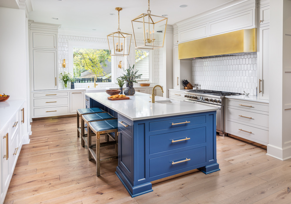 Transitional u-shaped light wood floor and beige floor kitchen photo in Nashville with a farmhouse sink, shaker cabinets, gray cabinets, white backsplash, stainless steel appliances, an island and white countertops