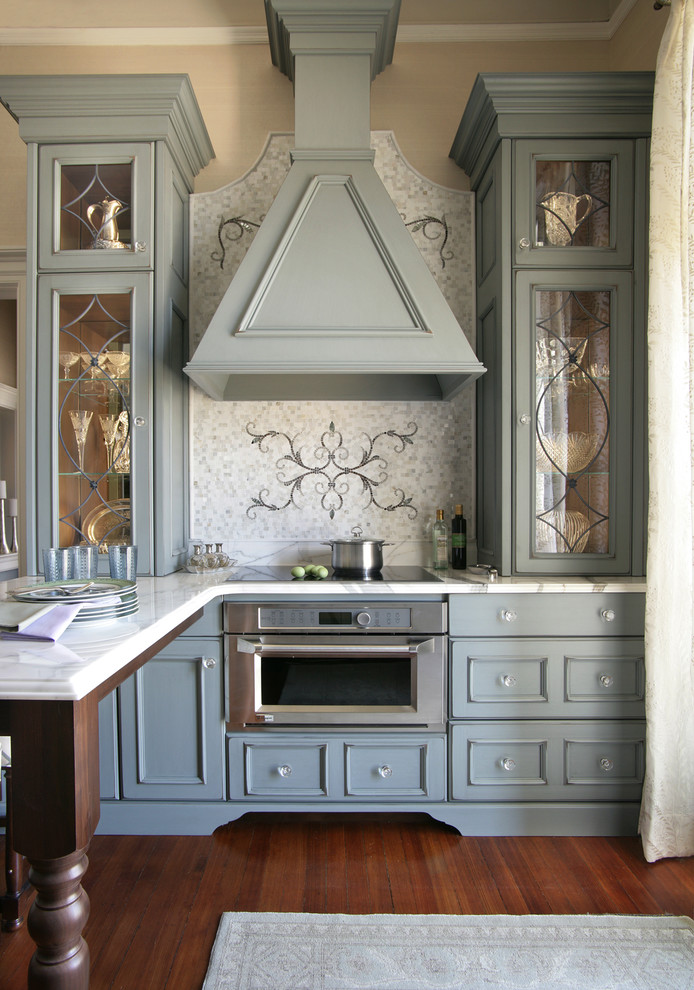 Exempel på ett litet klassiskt kök, med en nedsänkt diskho, rostfria vitvaror, mellanmörkt trägolv, en köksö, luckor med infälld panel, marmorbänkskiva, vitt stänkskydd, stänkskydd i marmor och grå skåp