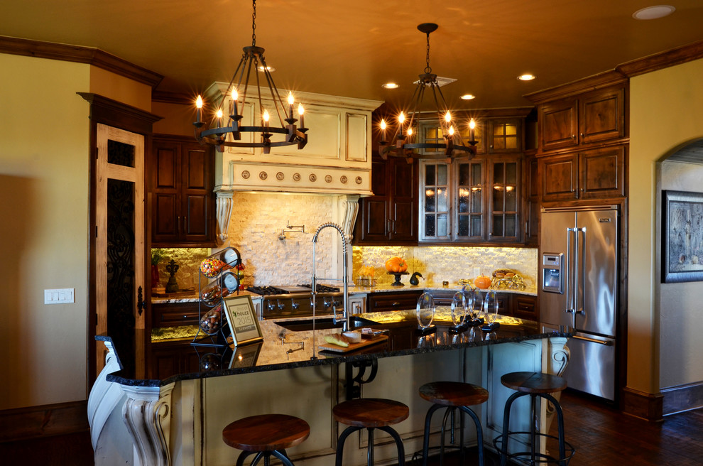 Bild på ett stort medelhavsstil kök, med en rustik diskho, luckor med upphöjd panel, skåp i mörkt trä, granitbänkskiva, beige stänkskydd, stänkskydd i stenkakel, rostfria vitvaror, mörkt trägolv och en köksö