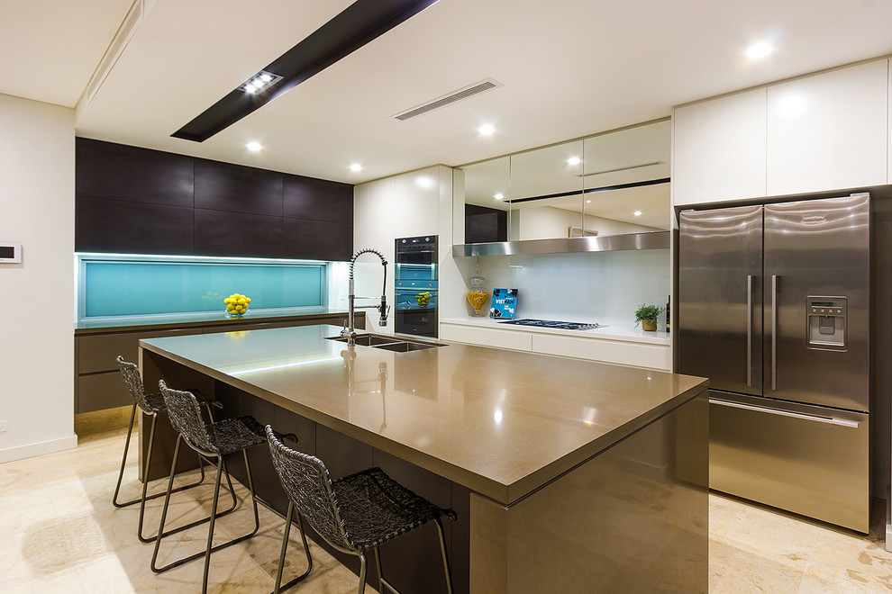 This is an example of a contemporary l-shaped kitchen/diner in Hobart with a double-bowl sink, flat-panel cabinets, white cabinets, blue splashback, stainless steel appliances and an island.