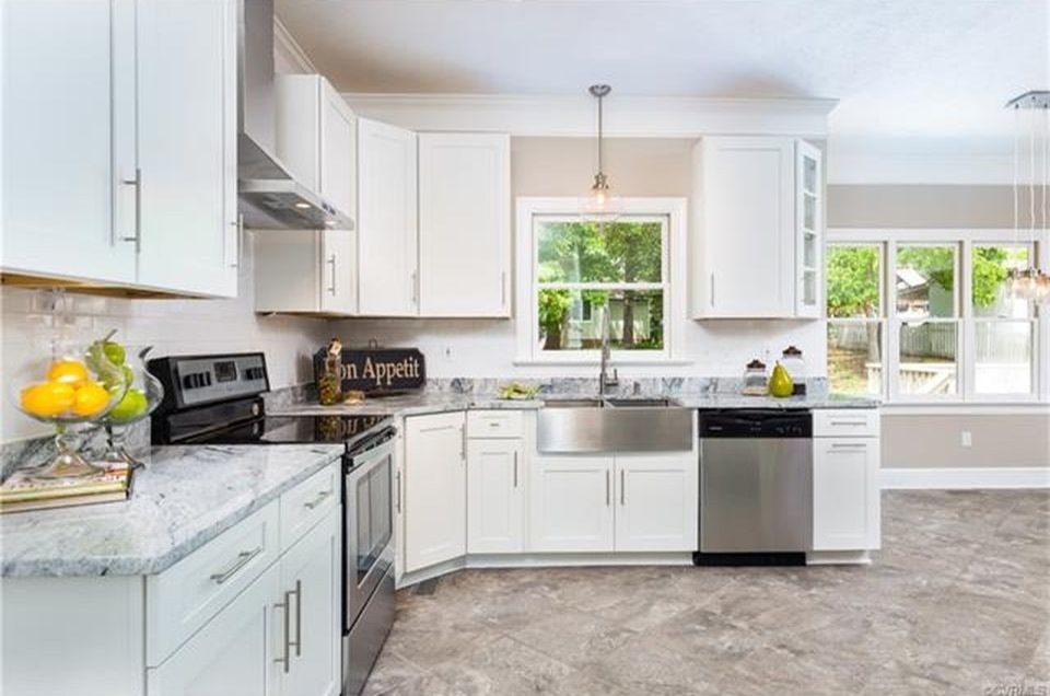 Immagine di una cucina a L moderna di medie dimensioni con lavello stile country, ante bianche, top in granito, paraspruzzi bianco, elettrodomestici in acciaio inossidabile e pavimento grigio