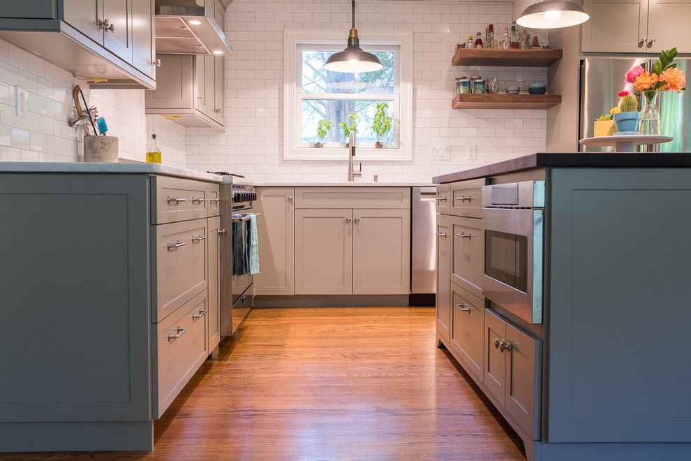 Inredning av ett modernt mellanstort kök, med en undermonterad diskho, skåp i shakerstil, grå skåp, bänkskiva i kvartsit, gult stänkskydd, stänkskydd i tunnelbanekakel, rostfria vitvaror, mellanmörkt trägolv, en köksö och brunt golv