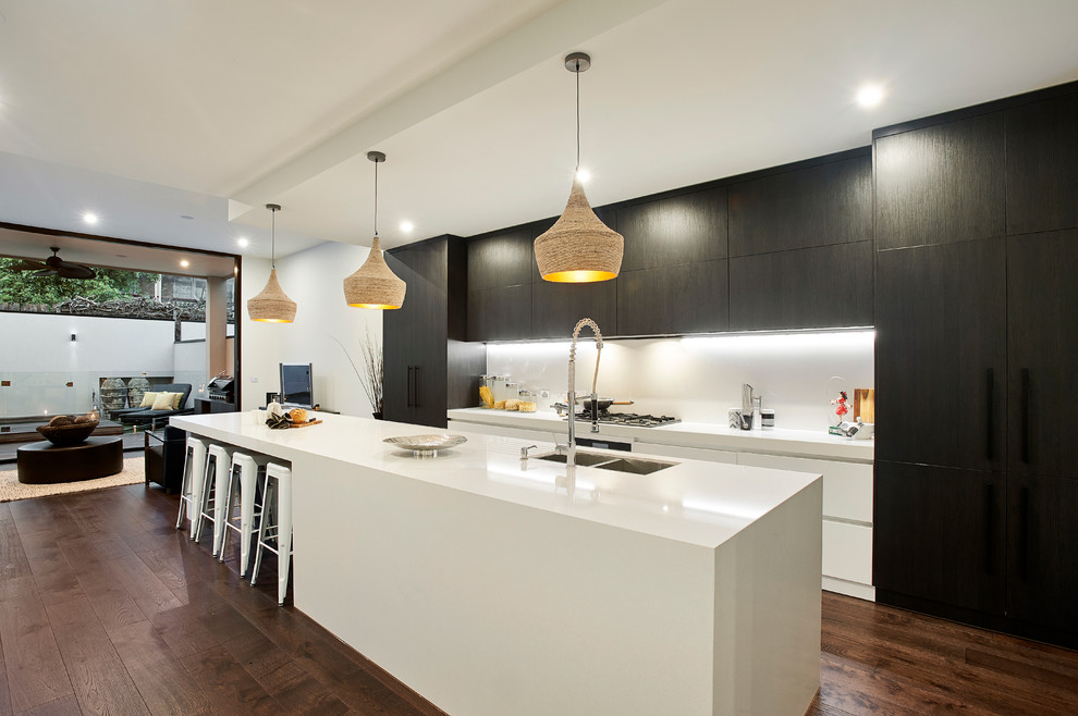 Moderne Küche mit Unterbauwaschbecken, flächenbündigen Schrankfronten, weißen Schränken, dunklem Holzboden und Kücheninsel in Melbourne
