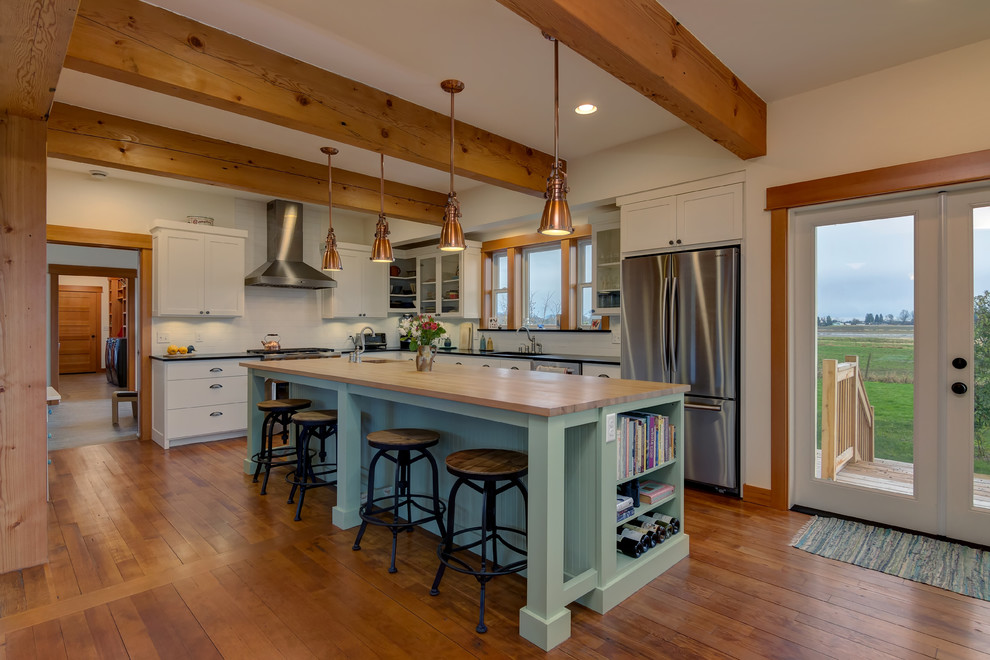 Large cottage l-shaped medium tone wood floor and beige floor eat-in kitchen photo in Seattle with a drop-in sink, raised-panel cabinets, white cabinets, wood countertops, white backsplash, subway tile backsplash, stainless steel appliances and two islands