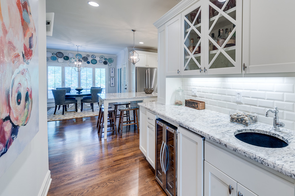 Eat-in kitchen - large traditional u-shaped dark wood floor eat-in kitchen idea in Kansas City with an undermount sink, glass-front cabinets, white cabinets, granite countertops, white backsplash, subway tile backsplash, stainless steel appliances and an island
