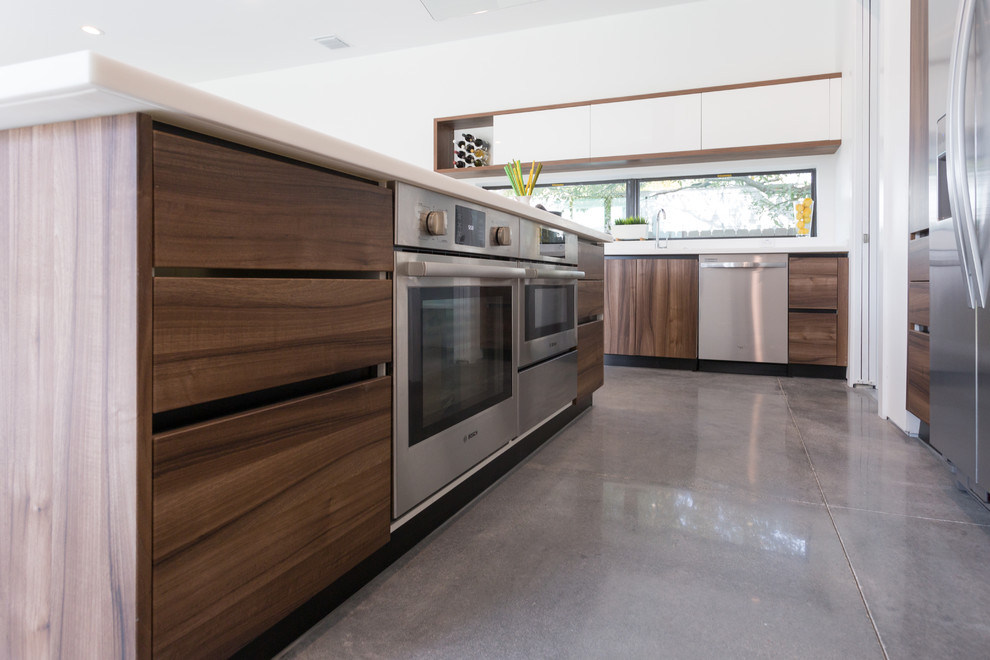 Ejemplo de cocina comedor moderna grande con armarios con paneles lisos, puertas de armario de madera en tonos medios, encimera de cuarzo compacto, electrodomésticos de acero inoxidable y una isla