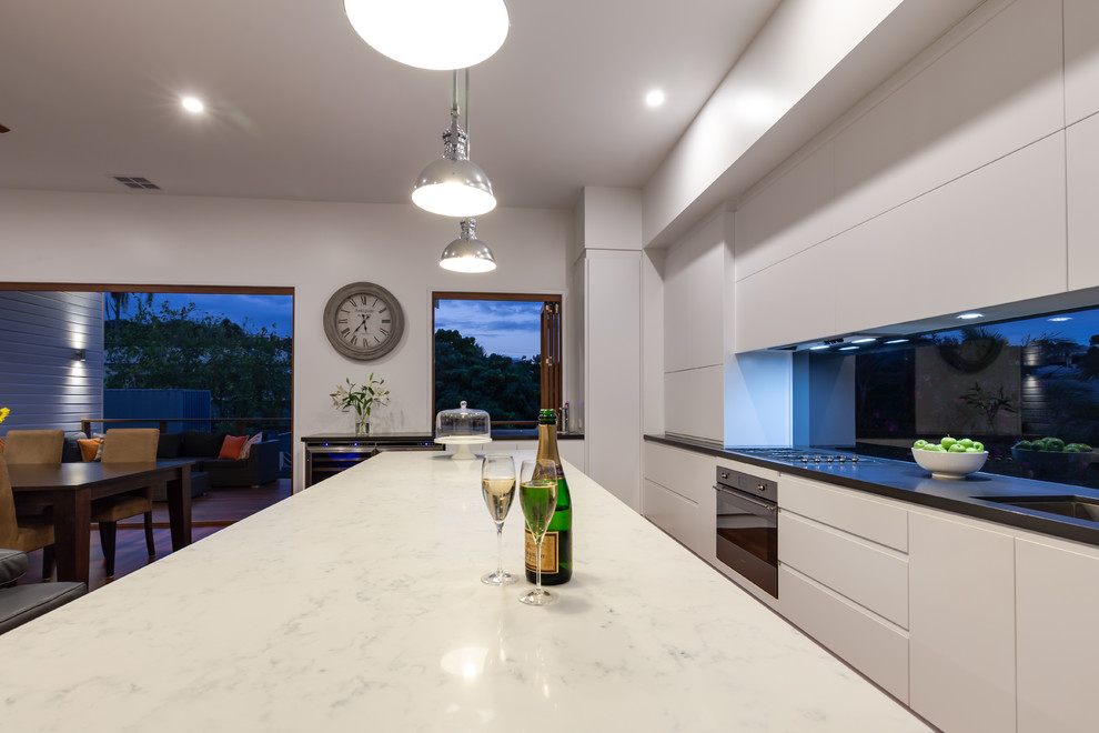 Medium sized contemporary single-wall open plan kitchen in Brisbane with a submerged sink, flat-panel cabinets, white cabinets, marble worktops, window splashback, stainless steel appliances, medium hardwood flooring and an island.
