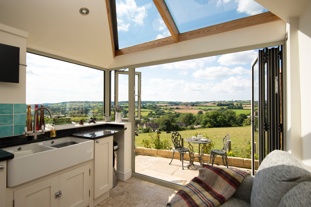 Photo of a small country single-wall kitchen in Buckinghamshire with a double-bowl sink, shaker cabinets, beige cabinets, blue splashback, no island, beige floors and black worktops.