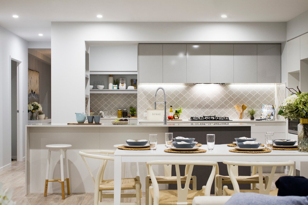 На фото: параллельная кухня-гостиная в морском стиле с плоскими фасадами, серыми фасадами, серым фартуком и полуостровом